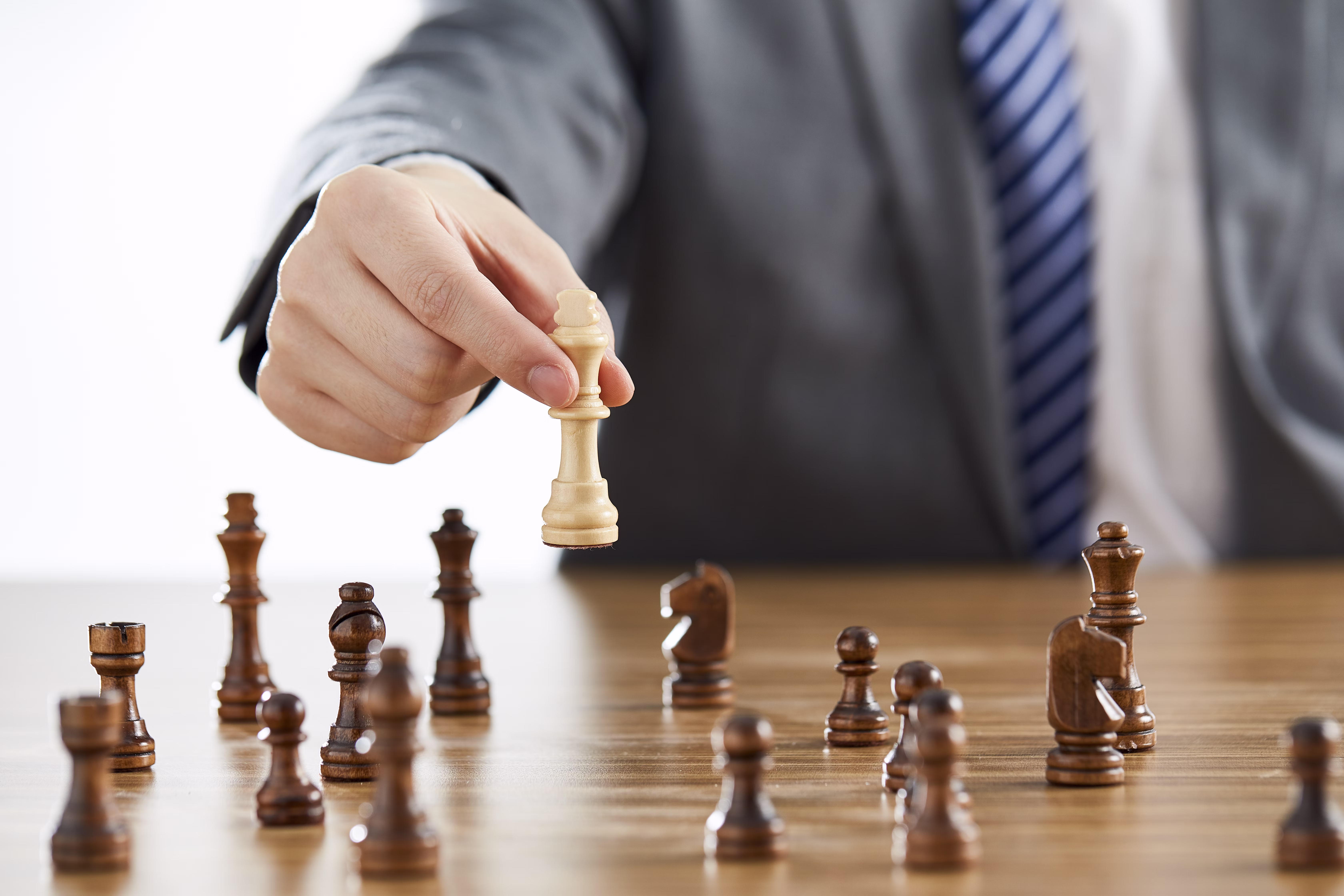 A businessman in a suit playing chess and about to win, reflecting the qualities of a strategic entrepreneurial leader.