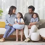 A family of four happily gathered on the living room couch, with a nearby HomePure ensuring clean and purified air.