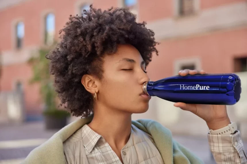A woman drinks from her HomePure reusable bottle, advocating health, cleanliness, and sustainability through hydration.