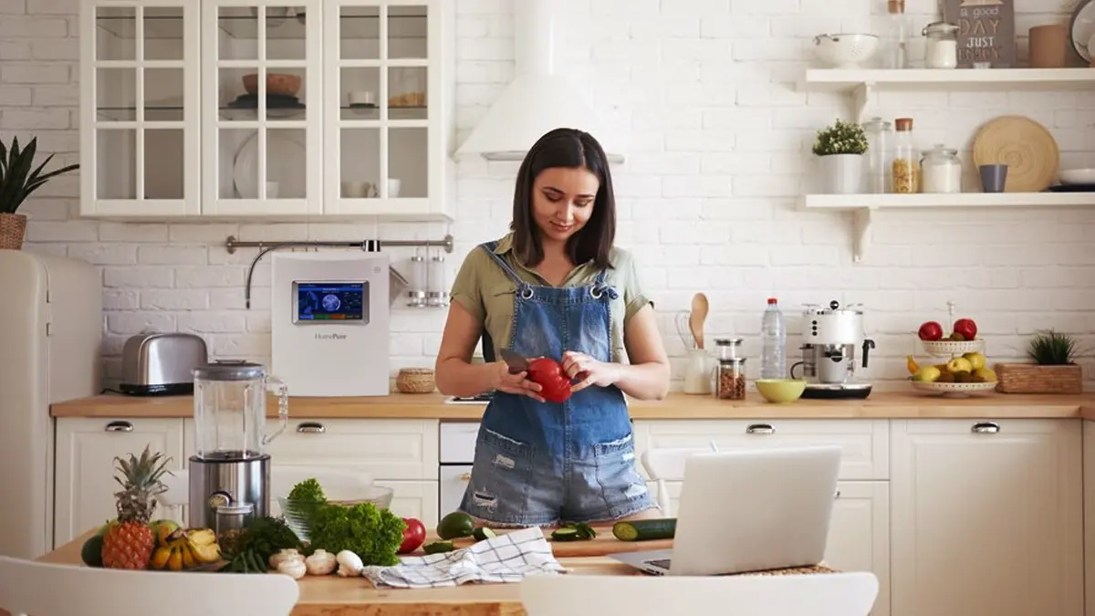 How To Stay Healthy And Consistent When Every Work Day Looks Different 3 Young woman in the kitchen cutting vegetables which she prepared with the help of HomePure Viva water