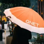 Monsoon Season Tips by QNET - girl with an orange umbrella